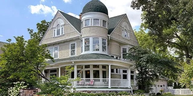 Queen Anne Victorian home with a domed turret, decorative gables, and wraparound porch.
