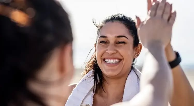 A woman smiling and high-fiving someone, conveying a sense of joy and accomplishment.