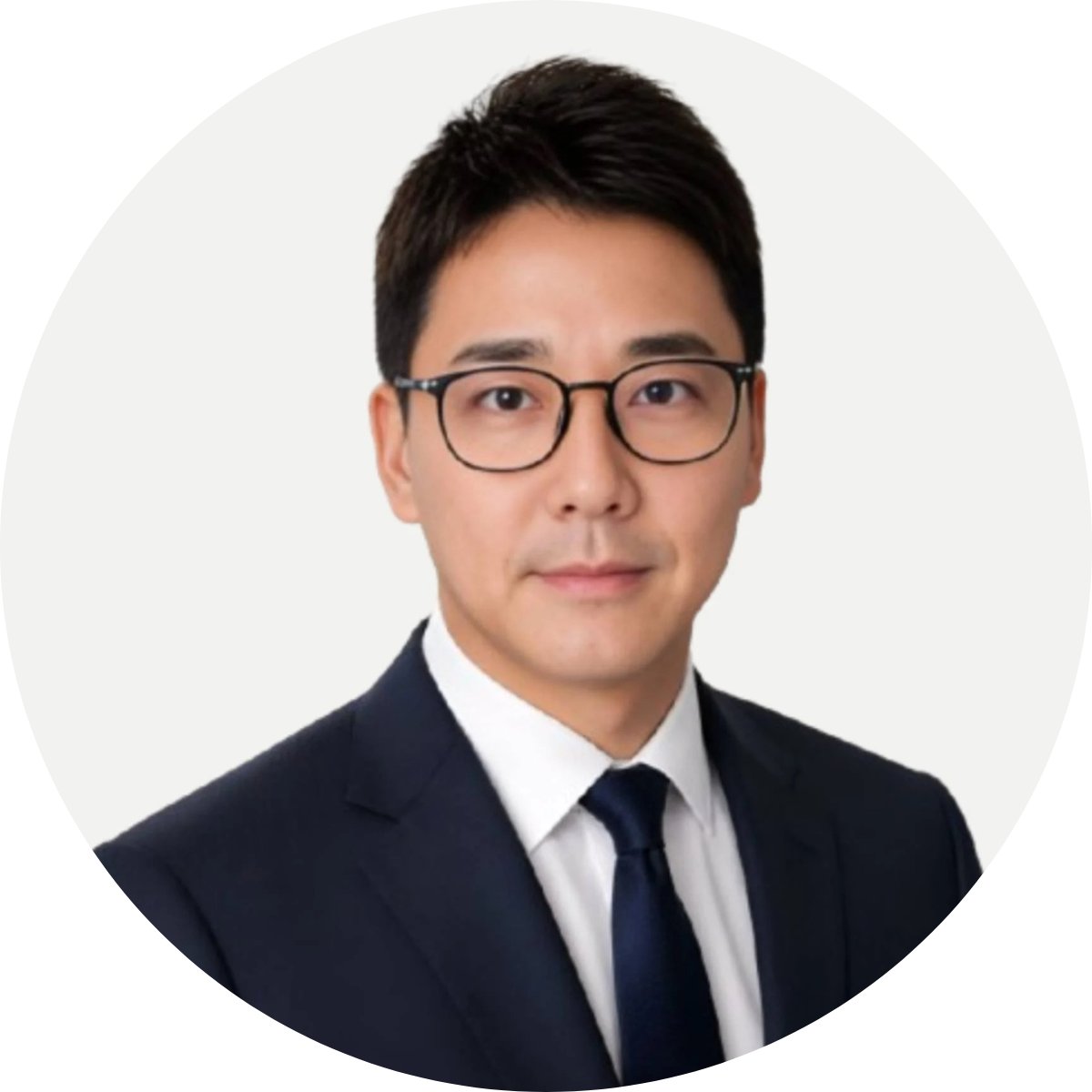 Mireu Lee wearing glasses, a dark suit, white shirt, and tie.