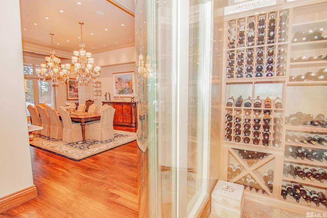 Dining room beside a glass-fronted wine cellar filled with bottles and built-in wooden racks.