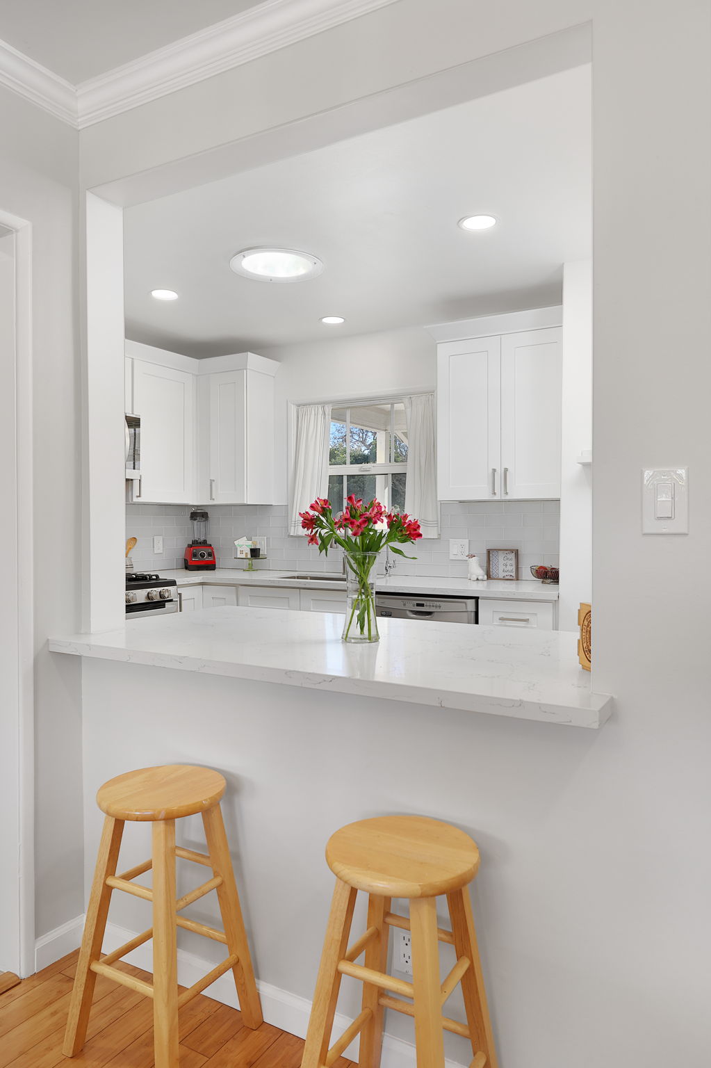Open-concept kitchen with pass-through breakfast bar and view into updated galley-style kitchen