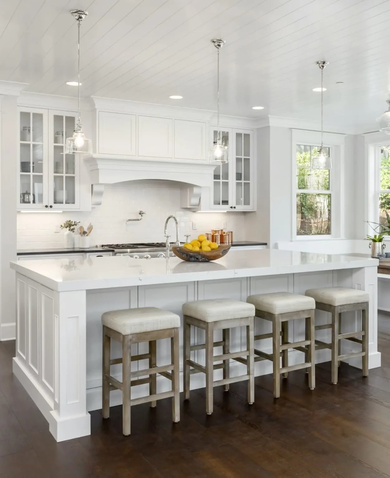 White kitchen in Philadelphia with a large island, four bar stools, and a bowl of lemons