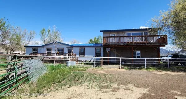 Single-story home with a raised wooden deck and fenced dirt yard.