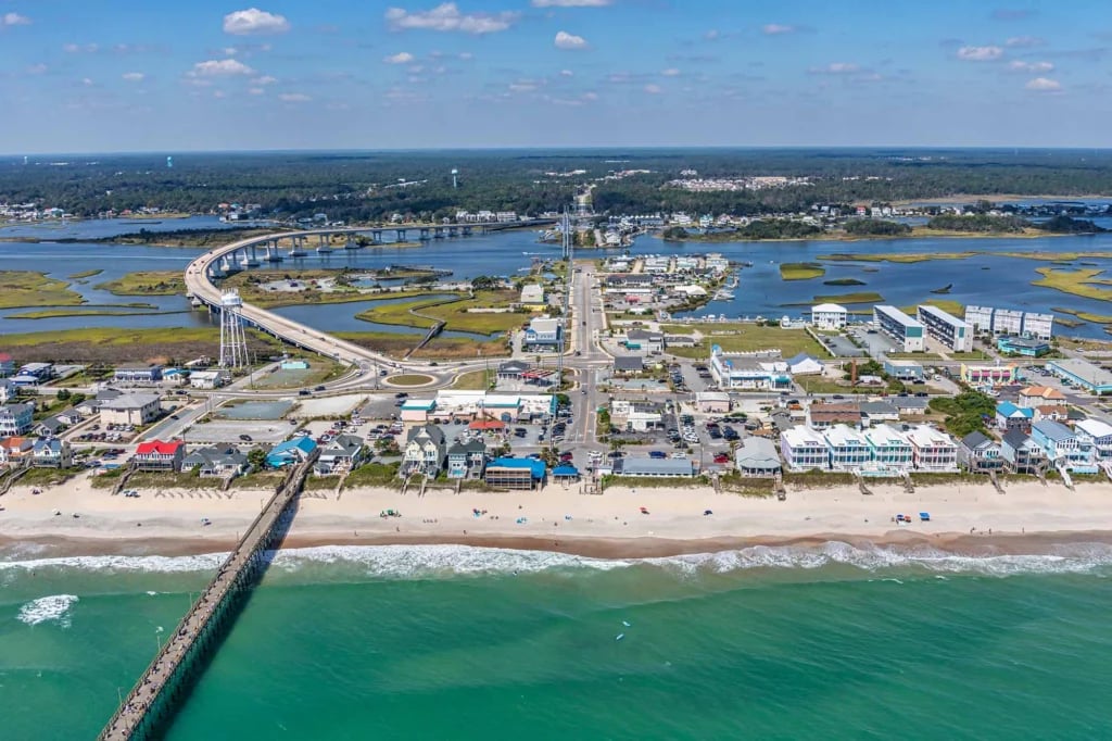 Aerial view of Surf City beach, with its fishing pier, oceanfront buildings, waterways, and bridge.