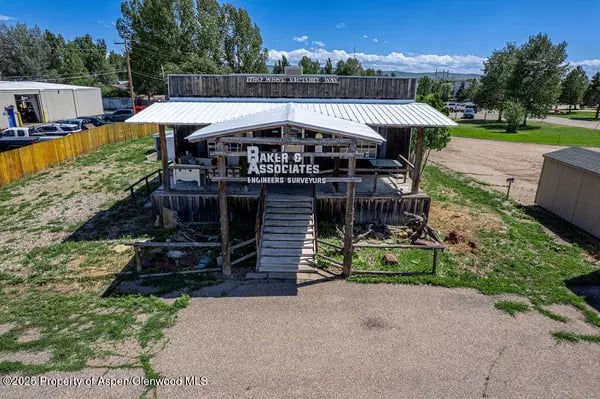 Commercial office building with a white metal roof, wooden deck, and Baker & Associates sign.