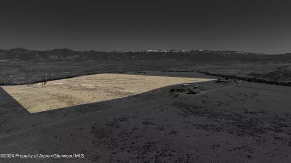 Aerial view of a highlighted vacant parcel with distant mountain views.