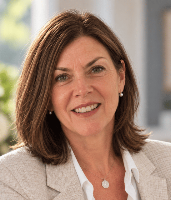 Karen Tyrell smiling in a light beige blazer and white blouse.