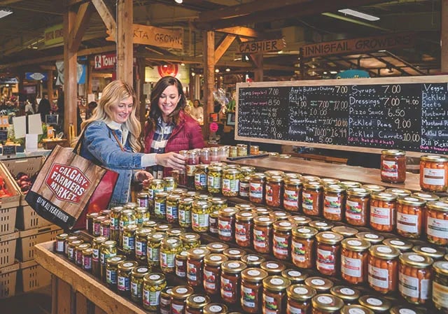 A vibrant scene capturing a woman shopping at the Calgary Farmers' Market, showcasing fresh produce and the lively atmosphere of the market.