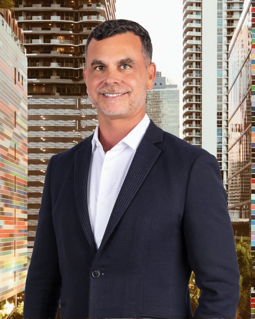 David Freed in a navy suit against a backdrop of modern high-rise buildings.