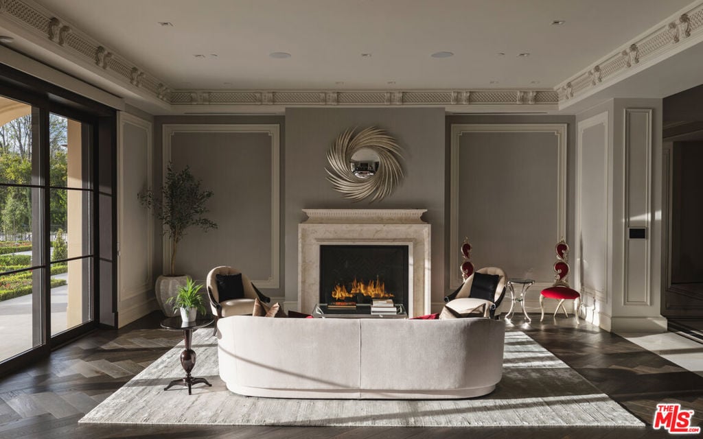 Formal living room with a curved white sofa, lit fireplace, and ornate ceiling molding.