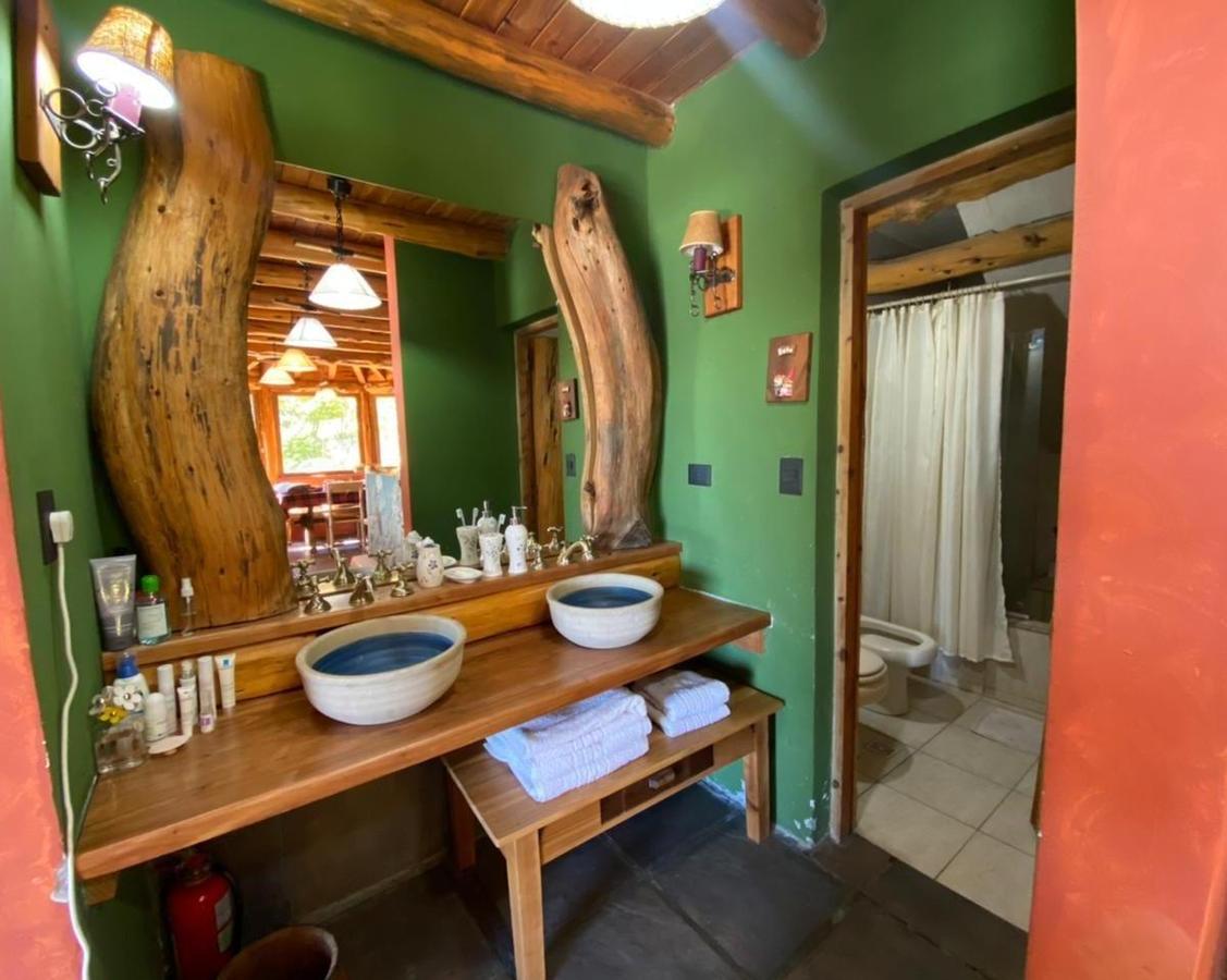 Rustic bathroom with a wooden double vanity, blue-and-white vessel sinks, and natural-log mirror supports.
