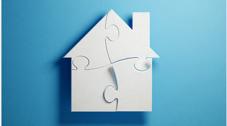 White puzzle pieces form a house against a blue background.