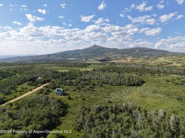 Aerial view of Craig-area countryside with a winding road, scattered homes, and distant mountains.
