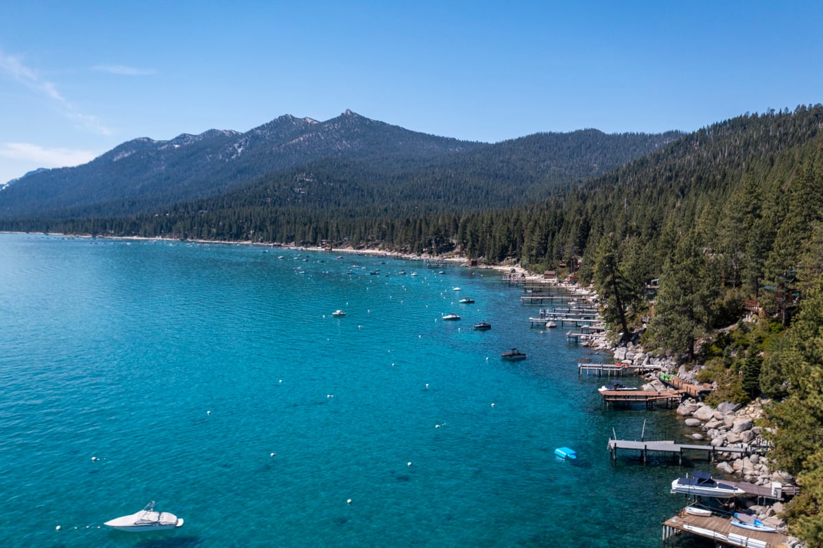 Aerial of lakefront piers and docks with mountain backdrop