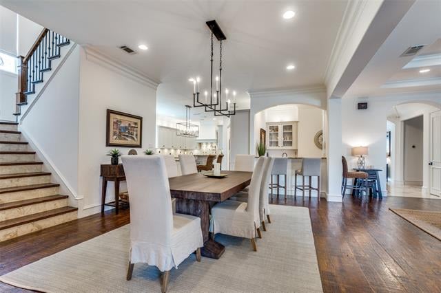 Dining room with a dark wood table, upholstered chairs, and an open view toward the kitchen.