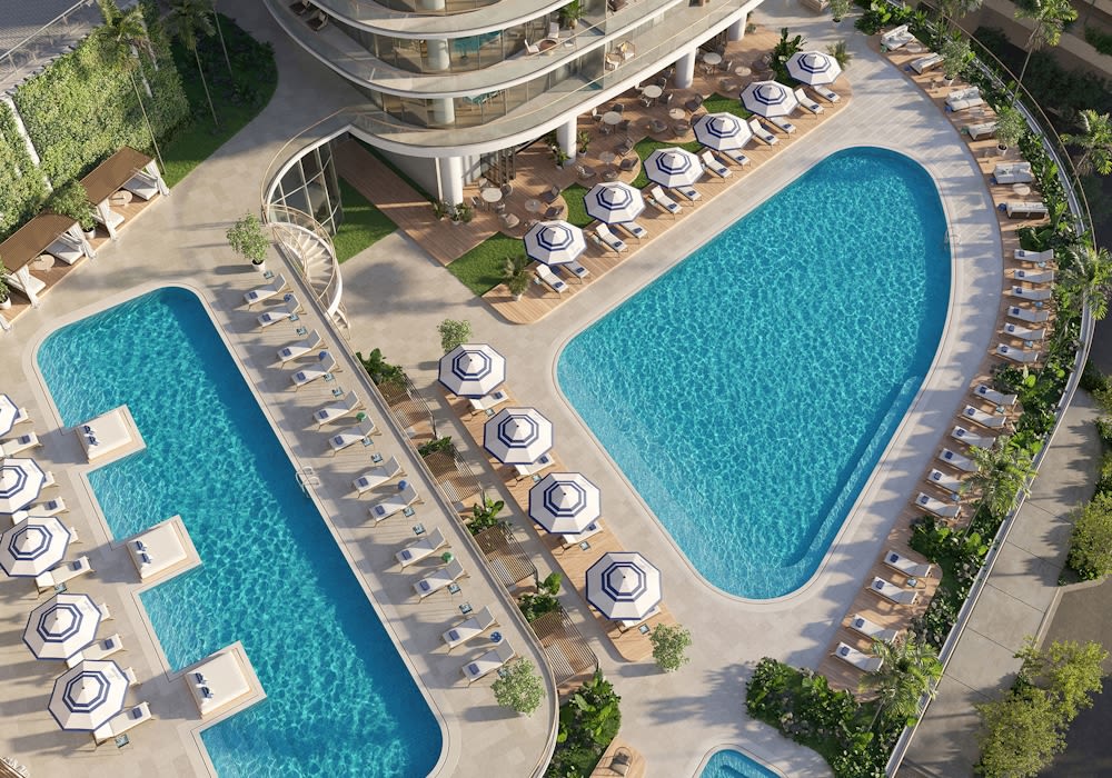 Cipriani Residences pool deck with two turquoise pools and rows of striped umbrellas.