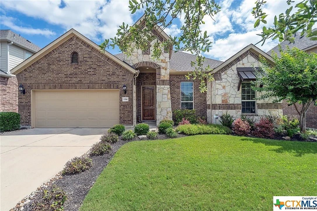 A photo of a brick house with a garage and a driveway