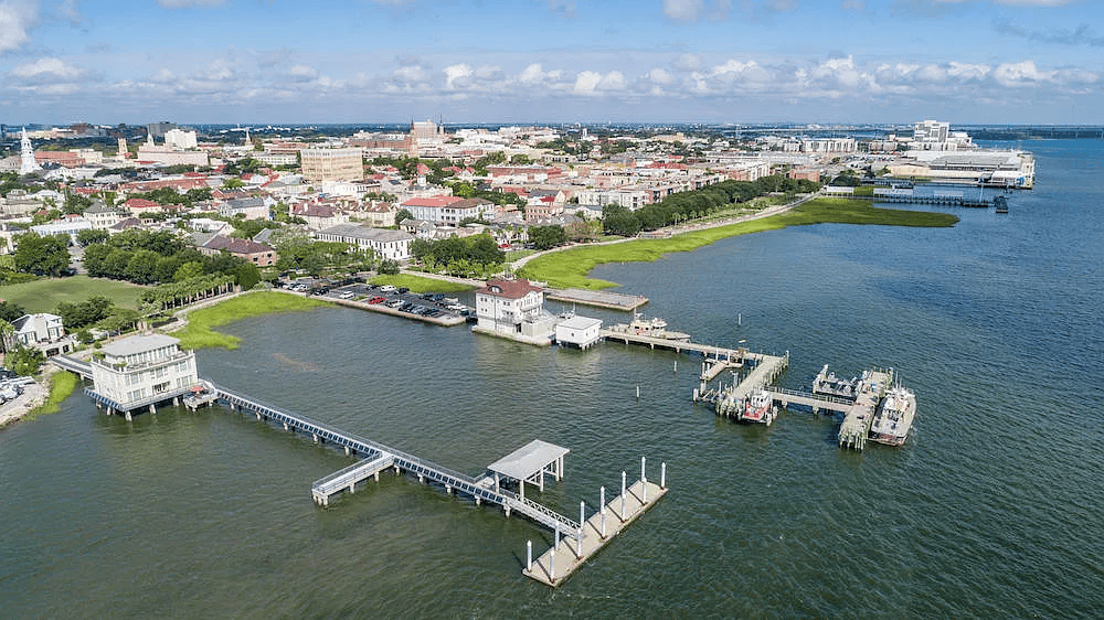 Charleston waterfront and city skyline across the harbor, with docks and piers in the foreground.