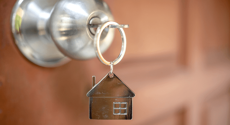 a key with a house keychain inserted to a door knob 