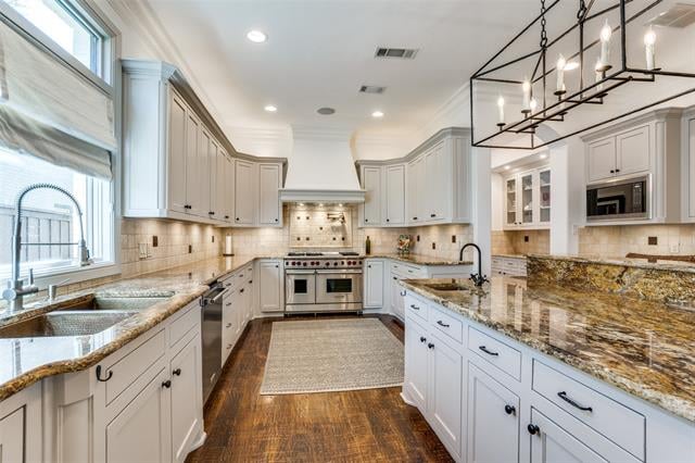 Bright kitchen with white cabinets, granite counters, and a large island beneath a black metal chandelier.