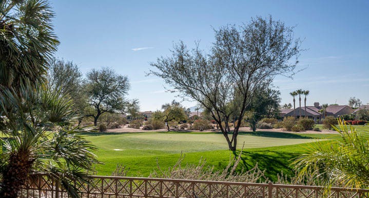 A golf course with trees and a fence in the foreground