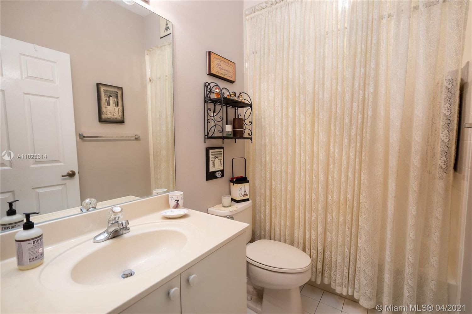 Bathroom with a white vanity, toilet, and patterned shower curtain.