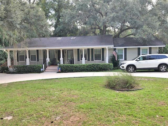 A single-story house in 5175 Velda Dairy Rd with a large front yard and a driveway. The house has a covered porch and is surrounded by trees, providing a serene and shaded environment.