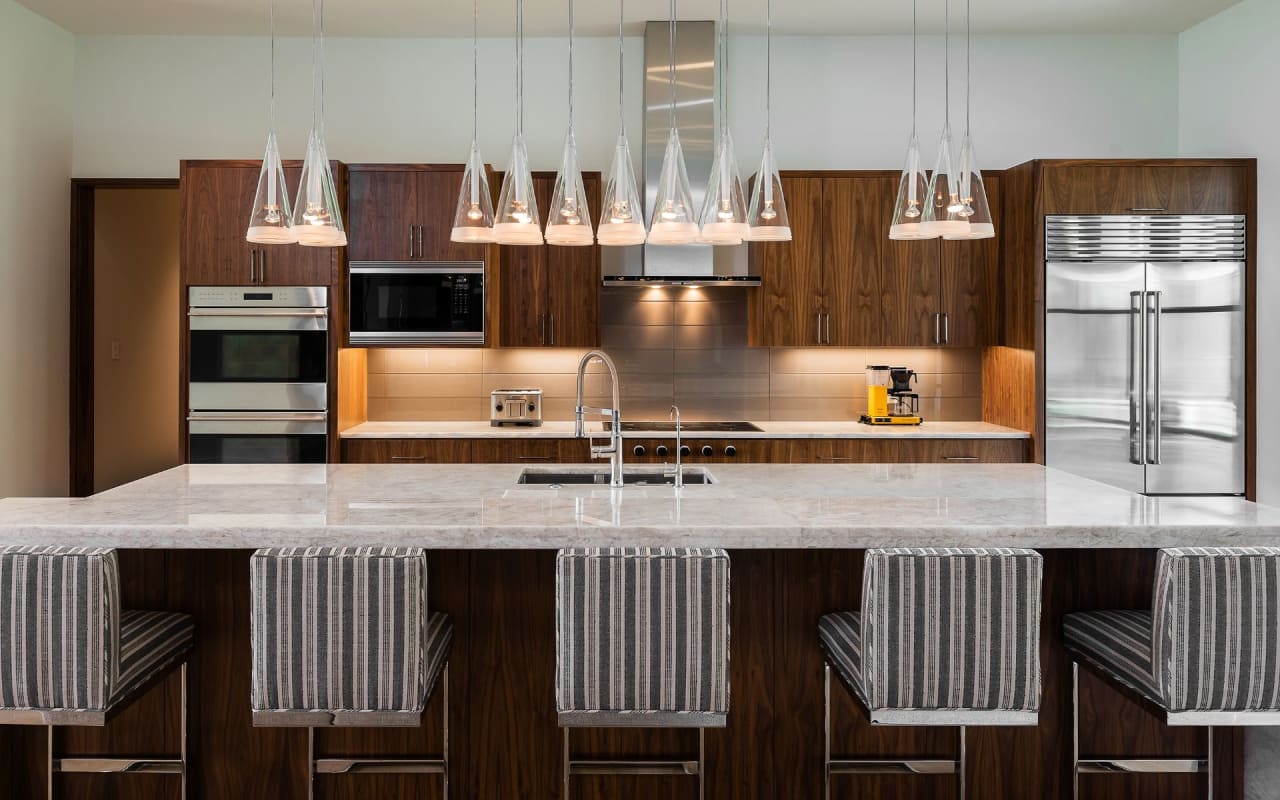 Refined modern kitchen with dark cabinets and striking chandeliers, adding luxury and sophistication to a culinary space.