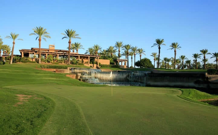 A golf course with a waterfall and palm trees