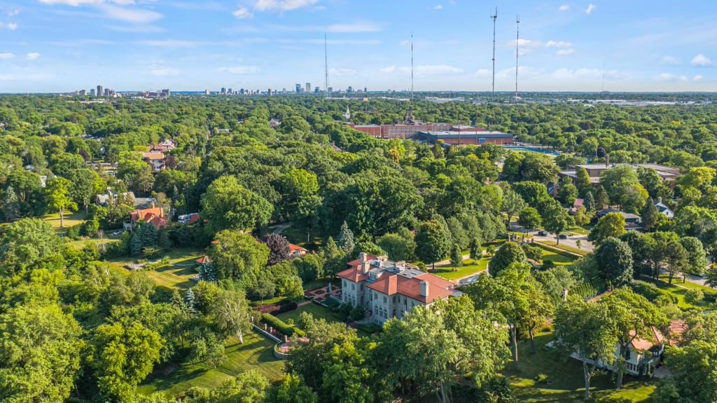 Aerial view of Milwaukee's North Shore homes and green landscape with Milwaukee skyline in the background.