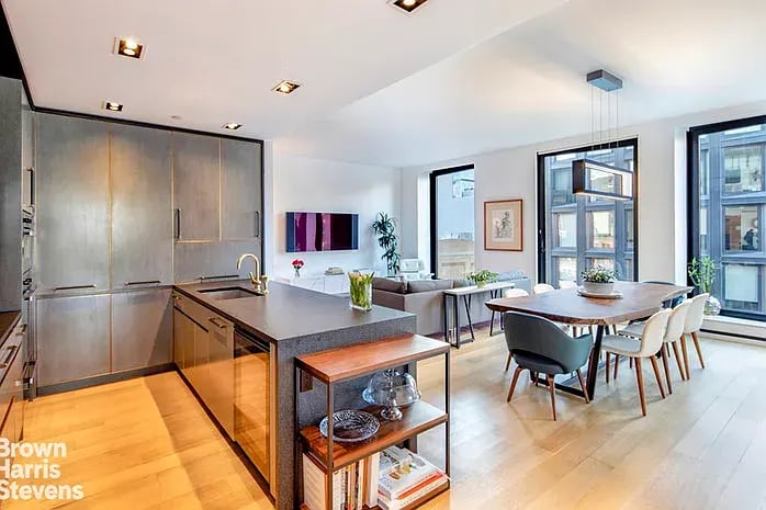 Open-plan kitchen and dining area with gray cabinetry, an island, and tall windows.