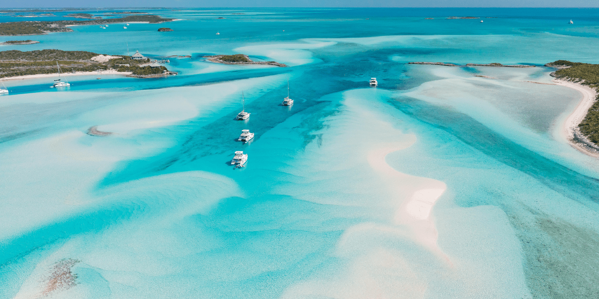 An aerial view of a group of boats sailing in a clear blue ocean.