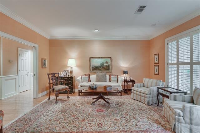 Living room with peach walls, a patterned rug, seating around a coffee table, and shuttered windows.