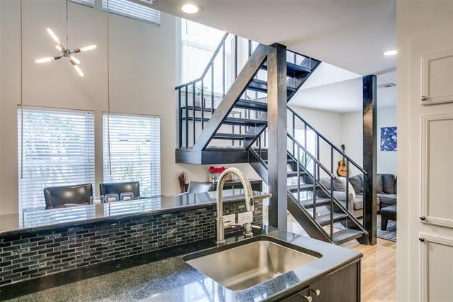 Modern condo kitchen with dark counters and a stainless sink, opening onto a striking open-riser staircase.
