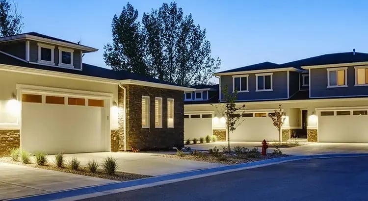 A large, modern house with well-lit exterior at dusk. The house has a spacious design with multiple levels and a landscaped yard.