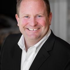 Stephen Amizich smiling in a black suit jacket and white shirt.