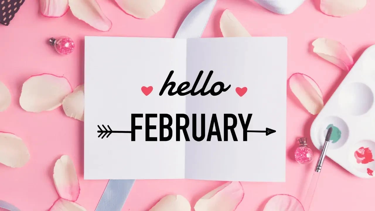 A festive design with the text "hello FEBRUARY" written on a white card. The background is pink with scattered petals and a light blue ribbon, giving it a celebratory and welcoming feel for the month of February.