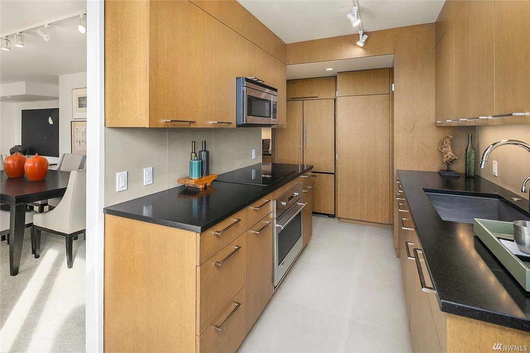 Modern condo kitchen with sleek wood cabinetry and dark countertops, offering a clean, upscale feel.