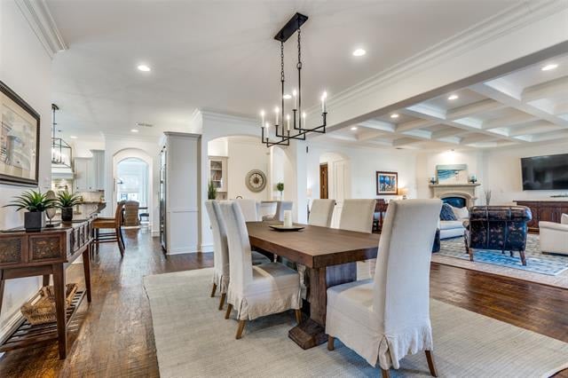 Dining room with a dark wood table, upholstered chairs, coffered ceiling, and adjoining living area.