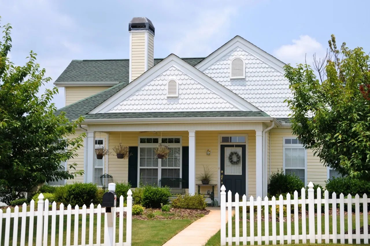  Charming house with a white picket fence, embodying the classic comfort of suburban home living.