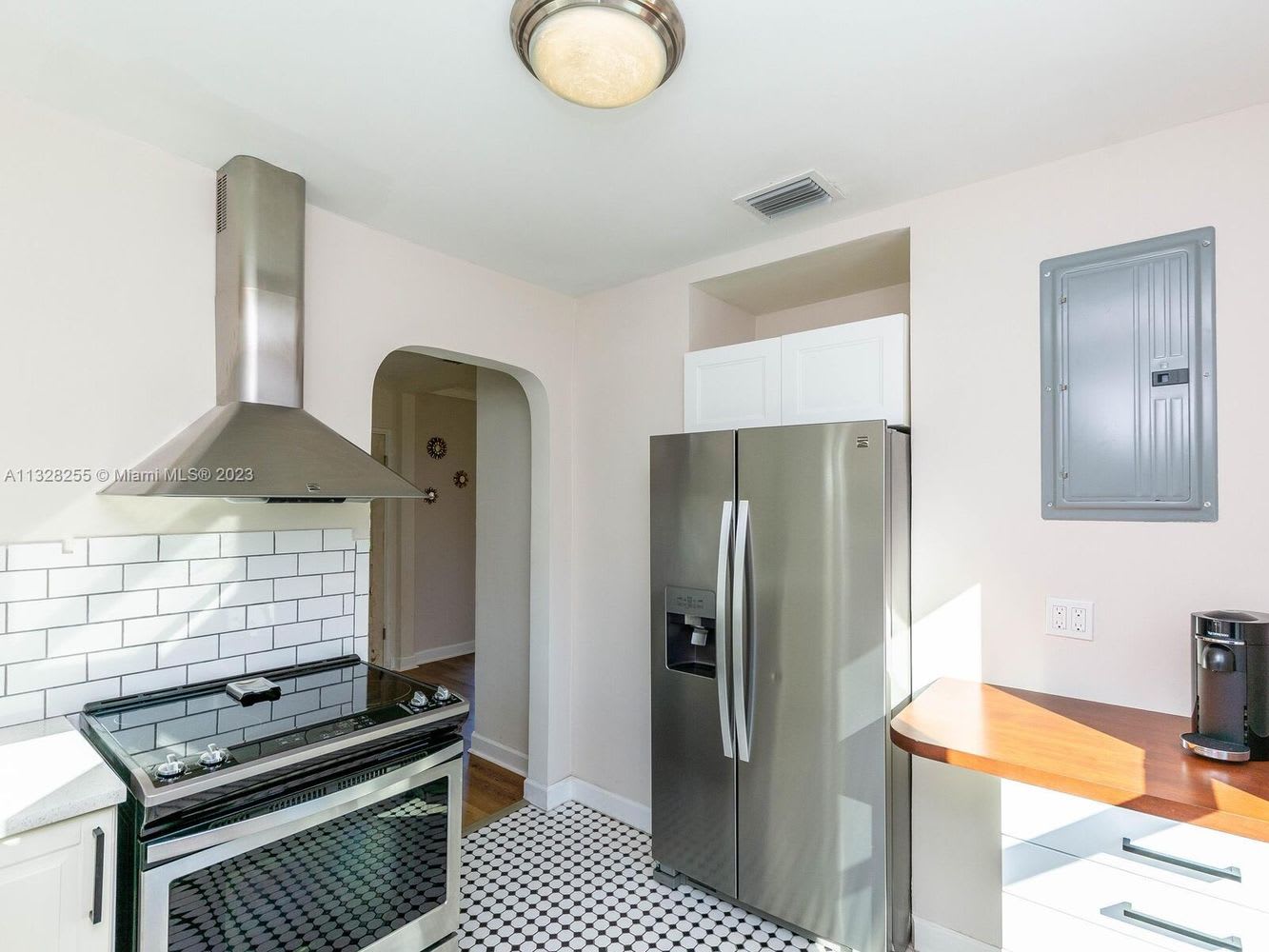 Kitchen with stainless-steel appliances, white subway tile backsplash, and patterned black-and-white floor.