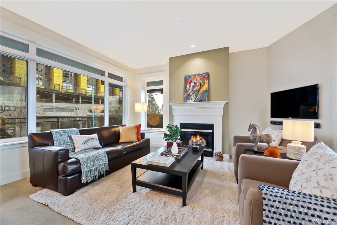 Living room in luxury home with cozy fireplace, elegant couch, stylish chair, and coffee table.