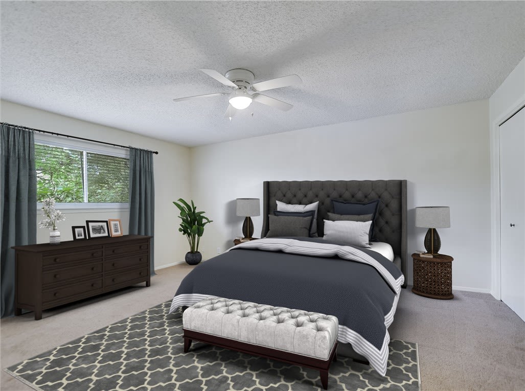 Bedroom with a dark tufted headboard, gray bedding, and a cushioned bench at the foot of the bed.