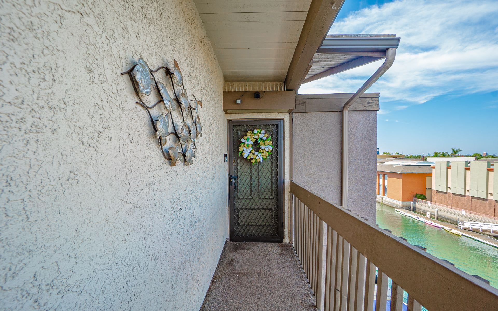 Covered condo entry with a wreath on the screen door and a canal beyond the railing.