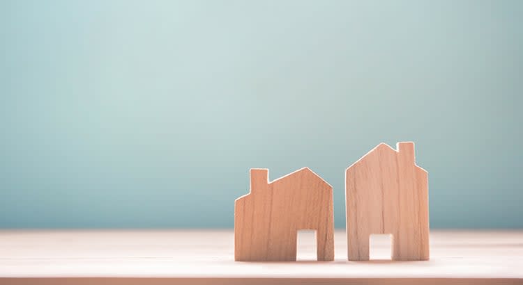 two small wooden house models placed side by side on a flat surface. 