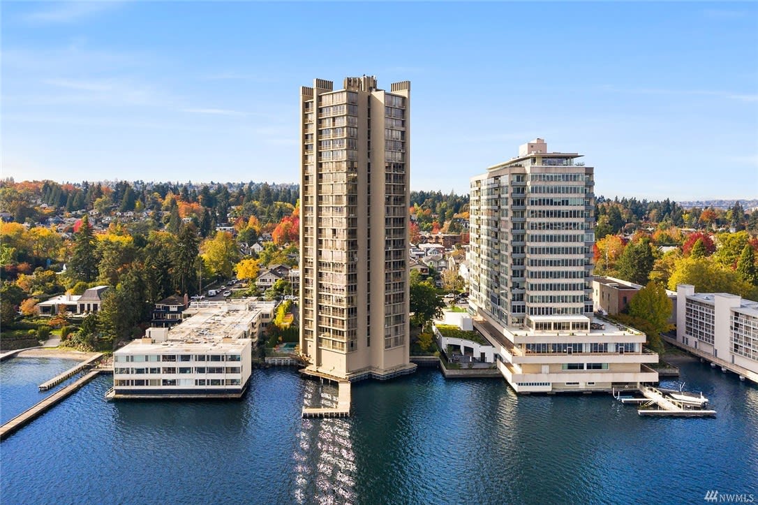 Aerial view of luxury waterfront condos amidst autumnal trees showcasing a serene and affluent living space.