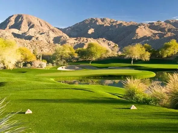 A golf course fairway with a pond and a green in the background.