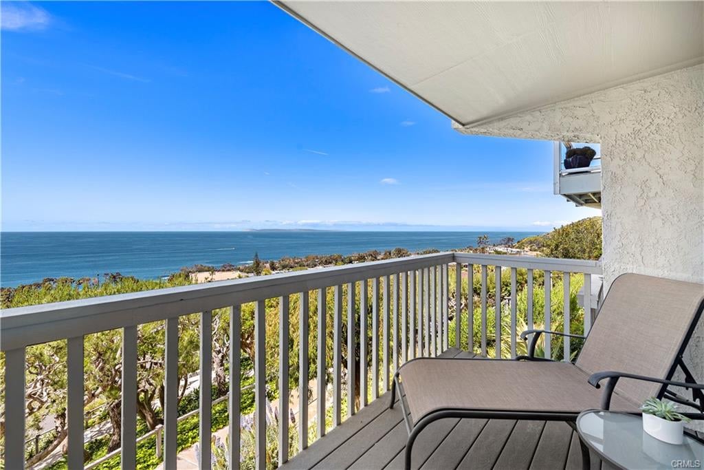 Ocean-view balcony with gray railing, lounge chairs, and a small table.