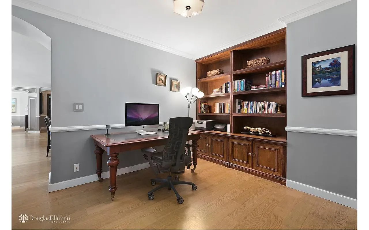 Home office with built-in wooden bookcases and a dark wood desk on hardwood floors.