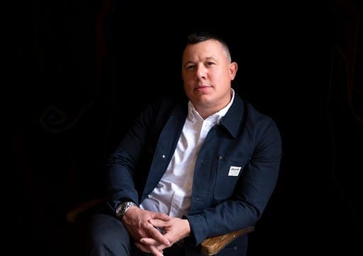 Bill Frost, a real estate professional from The Mike Seder Group, sitting on a chair wearing a jacket.